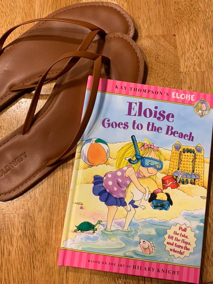 Picture of brown flip-flops and the book Eloise Goes to the Beach